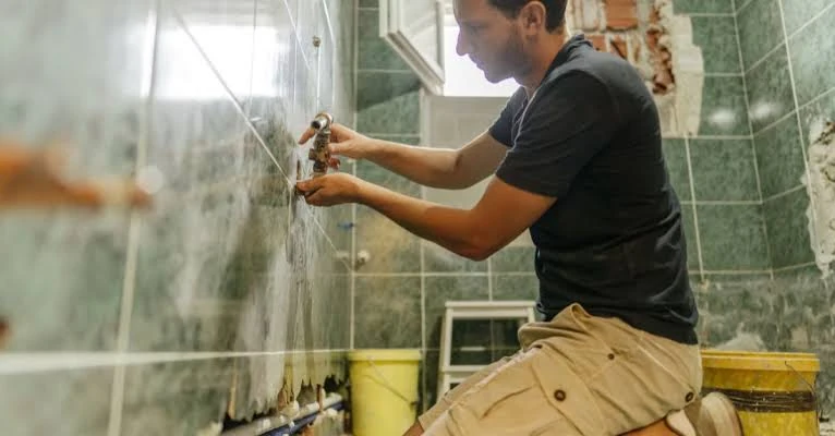 Illustrative photo of a person adjusting shower fittings during a bathroom renovation