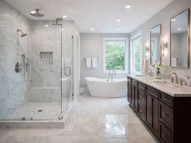 Gray marble bathroom with a frameless walk-in shower, freestanding tub and dark double vanity